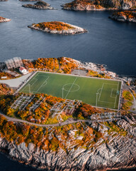 Aerial drone view of the famous Henningsvaer football field and fishing village on rocky islands surrounded by ocean water in Lofoten Norway © Quality by Simon