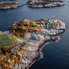 High angle aerial drone view of the famous Henningsvaer football field and lighthouse on rocky coast surrounded by ocean water in Lofoten Norway © Quality by Simon