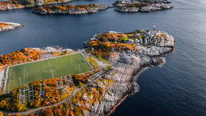 High angle aerial drone view of the famous Henningsvaer football field and lighthouse on rocky coast surrounded by ocean water in Lofoten Norway © Quality by Simon