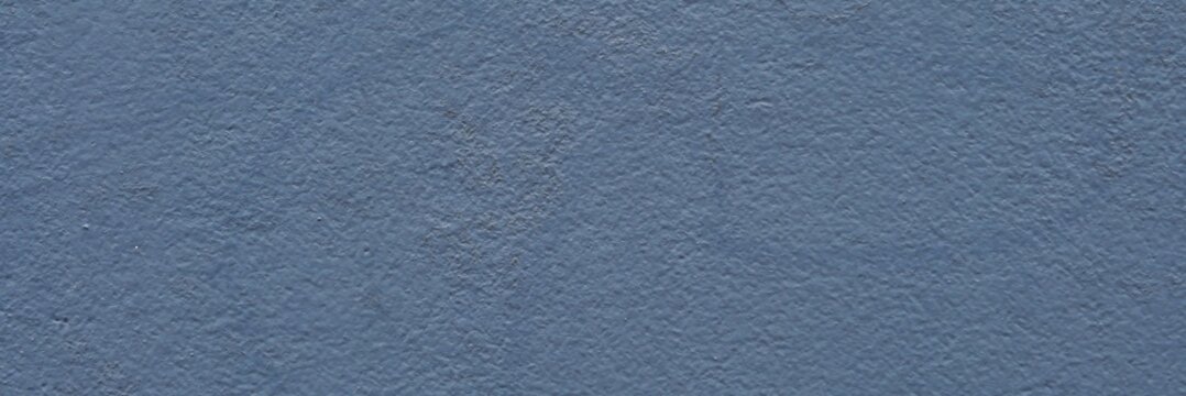 Blue painted concrete wall background with rough textured plaster surface