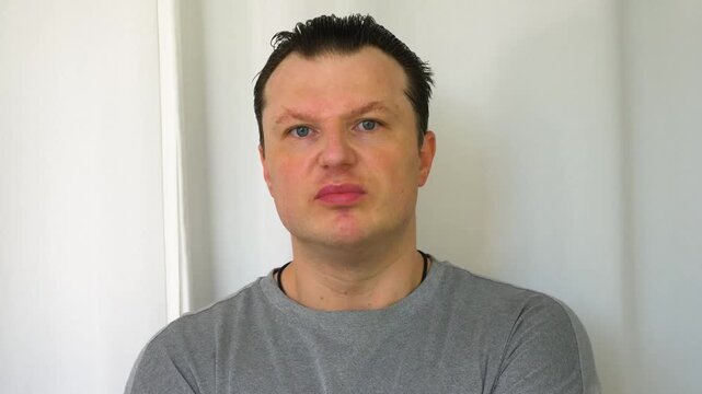 A person with a runny nose; a portrait of a young man against a white background. Sniffling, problems with the nasopharynx and breathing.