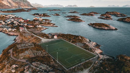 Vertical aerial drone view of the iconic Henningsvaer football field on a rocky island with scenic fjord and mountains in Lofoten Norway © Quality by Simon