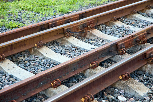 Dual gauge railway tracks showing rusty European standard rail beside shiny broad gauge line at closed border post with concrete sleepers and gravel ballast during sanctions period