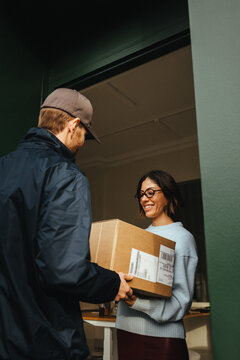 Courier completes a delivery as a woman receives the parcel at the office door