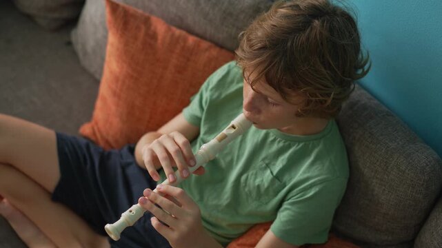 A little boy learns to play the flute at home, practicing with focus and enthusiasm in a cozy, warm setting. A charming scene of early musical exploration, creativity, and childhood growth.