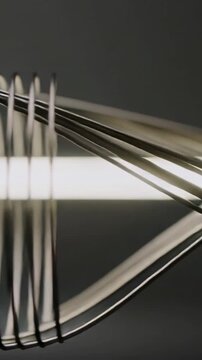 Vertical video: Turning tube light making coil pages folding and sliding in studio creating moire