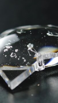 Vertical video: Tilting macro lens revealing glass shard with tiny chips on black pad