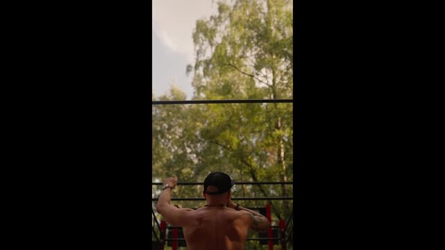 An athlete hangs from a pull-up bar at an outdoor park playground