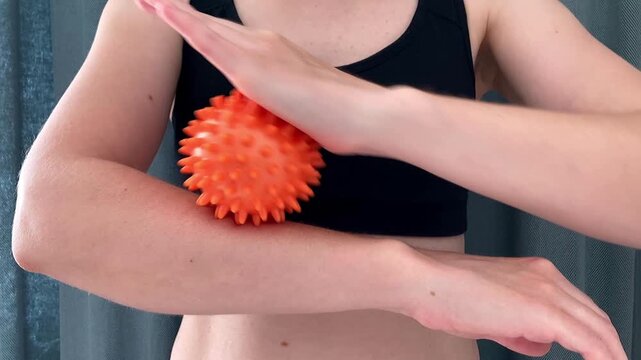 The woman practices self‑massage using an orange massage ball at home, to reduce the feeling of tension the muscles and maintain normal blood circulation. Close-up
