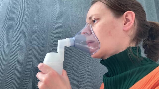 The woman is performing an inhalation procedure at home, treating seasonal illnesses using a nebulizer. The topic is prevention, home care, and maintaining the health of the respiratory system