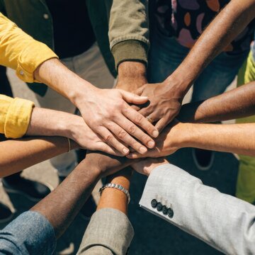 Diverse group of people stacking hands in unity diversity