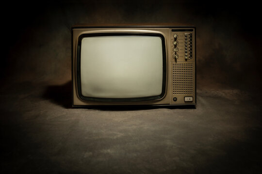 Retro old TV receiver with blank screen on floor with a dark background, front view