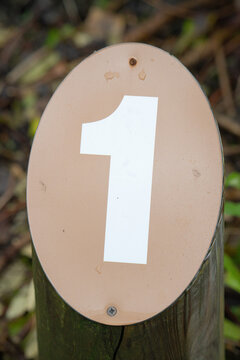 Close-up of a number one trail marker attached to a weathered wooden post