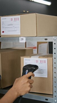 Vertical video of unrecognizable worker scanning barcodes on cardboard parcels with laser scanner for inventory tracking. Clip ideal for logistics, supply chain, and retail business promos