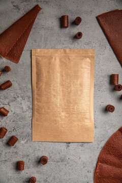 Natural fruit leather rolls and sheets arranged around craft paper ziplock pouch mock up on grey concrete background