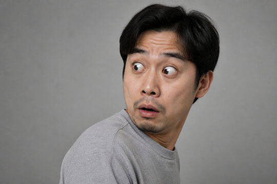 Surprised adult with wide eyes on gray background, shock and unexpected news concept