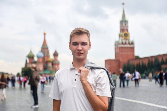 Young man with light hair white clothes standing on Red Square in Moscow, Russia. Famous historical landmark travel tourism concept.