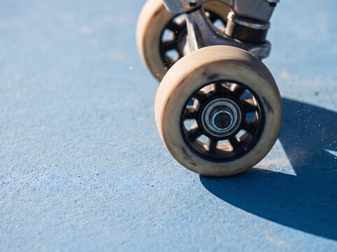 Skateboard wheels frozen mid spin with radial 
shadow pattern against cloud blue surface and 
copy space