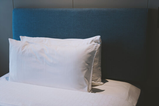 Modern hotel bedroom with white pillows and blue headboard in a sleek minimalist room &mdash; clean