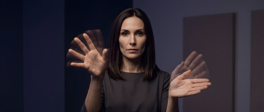Businesswoman leader portrait, motion blur fast hand movements interacting with virtual space, elegant grey attire, dark blue corporate office studio, future innovation tech advertising assets.