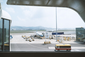 Fototapeta premium Airport tarmac view through terminal window with aircraft and ground vehicles