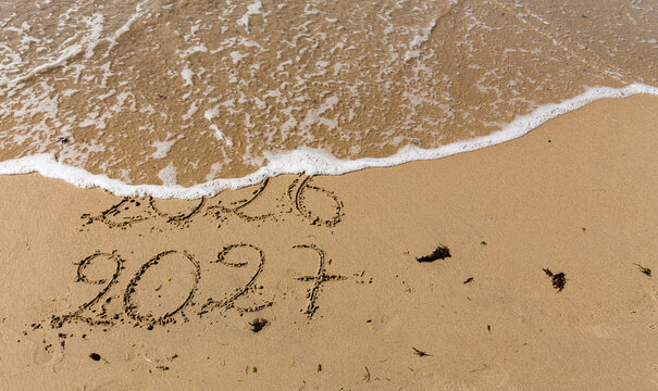 Bonne et heureuse ann&eacute;e 2027, &eacute;l&eacute;gante carte de voeu montrant la fin de 2026 et le passage &agrave; 2027 sur le sable d'une plage. Slogan &agrave; ajouter