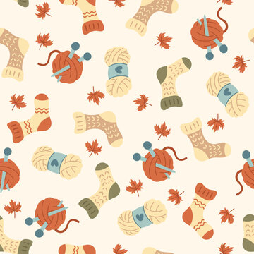 Vector seamless knitting pattern with yarn, needles, wool socks, skeins and autumn leaves. Cozy handmade craft texture for textile, fabric, wrapping paper, wallpaper, background, seasonal print