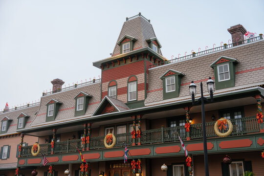A Victorian hotel in St. Augustine, Florida, features a tall mansard roof and rows of dormer windows. Glowing wreaths, red bows, garlands, ornaments, and international flags decorate the long balcony.