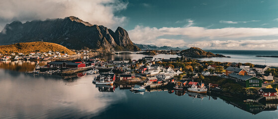 High angle panoramic view of Reine village with red cabins and bridges surrounded by fjord and mountains in Lofoten Norway © Quality by Simon
