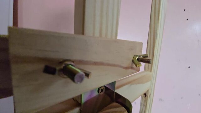 Close-Up Panning View of Wooden Studio Easel Frame, Wing Nuts, Bolts, and Metal Bracket Connector   