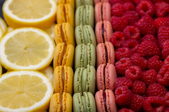 macaroons of different colors with raspberries and lemon