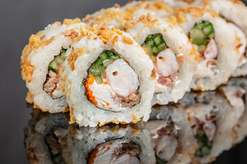 Close up of sliced sushi rolls with rice, cucumber, seafood filling, orange roe, crispy topping, and glossy reflection on a dark surface, Japanese cuisine © Надія Коваль