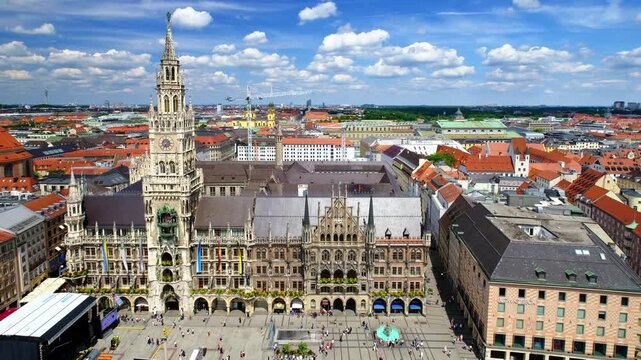 Wide aerial view from St Peter tower over Neues Rathaus and Marienplatz in Munich, Germany, with red rooftops and summer clouds