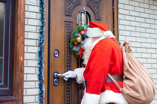 Santa Claus opens the decorated front door.