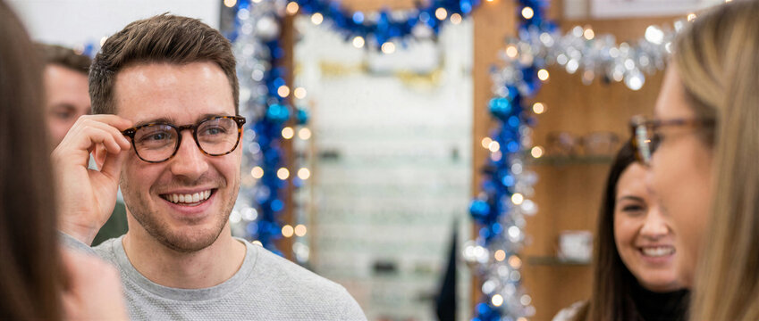 Man trying on eyeglasses in Christmas optical store