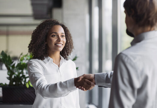 Young business people shaking hands while working. Handshake in creative office. Business, lifestyle, employment, new business, job interview, people concept