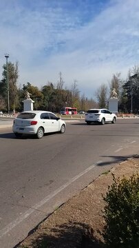 General San Mart&iacute;n Park - Marly's Horses: A clear, sunny day with cars driving on a wide road, flanked by trees and ornamental statues on either side, hinting at an urban entrance or parkway - 