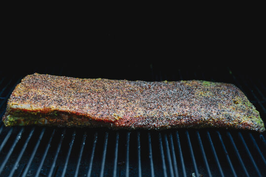 Barbecue pork ribs seasoned with salt, pepper, garlic for a crunchy bark. The bbq meat is cooking on a pellet grill smoker. 