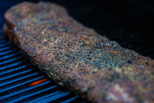 Barbecue pork ribs seasoned with salt, pepper, garlic for a crunchy bark. The bbq meat is cooking on a pellet grill smoker. 