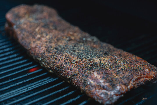 Barbecue pork ribs seasoned with salt, pepper, garlic for a crunchy bark. The bbq meat is cooking on a pellet grill smoker. 