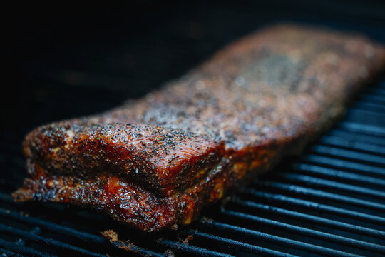 Pork ribs on a barbecue pellet grill smoker with salt and pepper seasoning. The bbq meat is tender and delicious. 