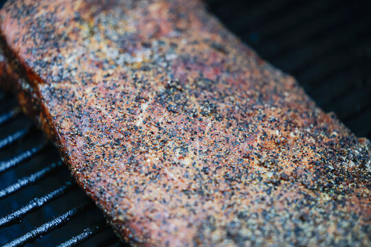 Barbecue pork ribs seasoned with salt, pepper, garlic for a crunchy bark. The bbq meat is cooking on a pellet grill smoker. 