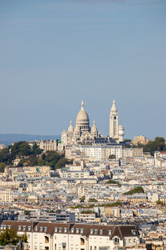 Panoramic Paris cityscape featuring Sacr&eacute;-C&oelig;ur Basilica and Montmartre at sunrise, with urban rooftops, clear sky and ample copy space