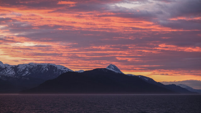 Breathtaking Alaska mountain glacier range view seen from outdoor deck of cruise ship liner sailing the Inside Passage transit with spectacular landscape scenery during sunset