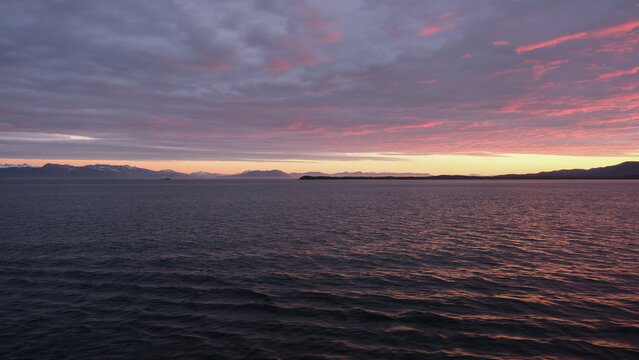 Breathtaking Alaska mountain glacier range view seen from outdoor deck of cruise ship liner sailing the Inside Passage transit with spectacular landscape scenery during sunset