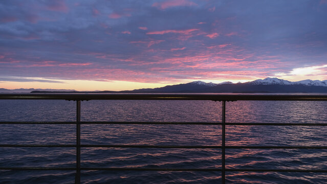 Breathtaking Alaska mountain glacier range view seen from outdoor deck of cruise ship liner sailing the Inside Passage transit with spectacular landscape scenery during sunset