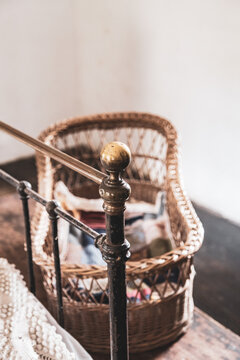 Wicker Baby Crib At The Bottom Of A Vintage Brass Bedstead