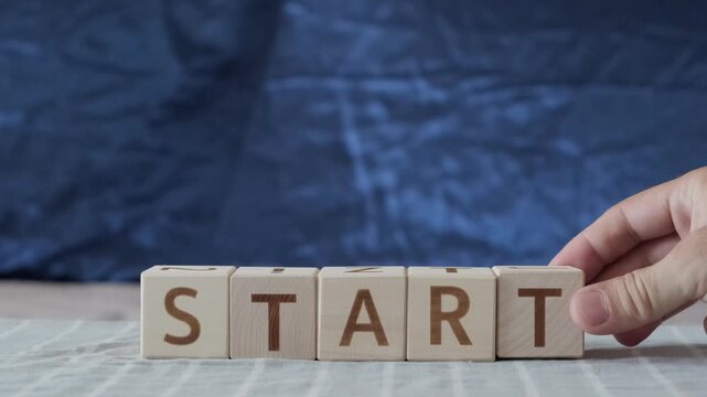 motivational word Start, laying out  by hand from letters on wooden cubes, slow motion
