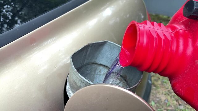 Refueling filling car benzine gasoline fuel at gas station from canister,funnel into automobile's tank,petrol prices.Gasoline, petroleum.