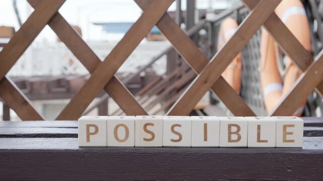 motivational word Impossible Possible, laying out  by hand from letters on wooden cubes, slow motion
